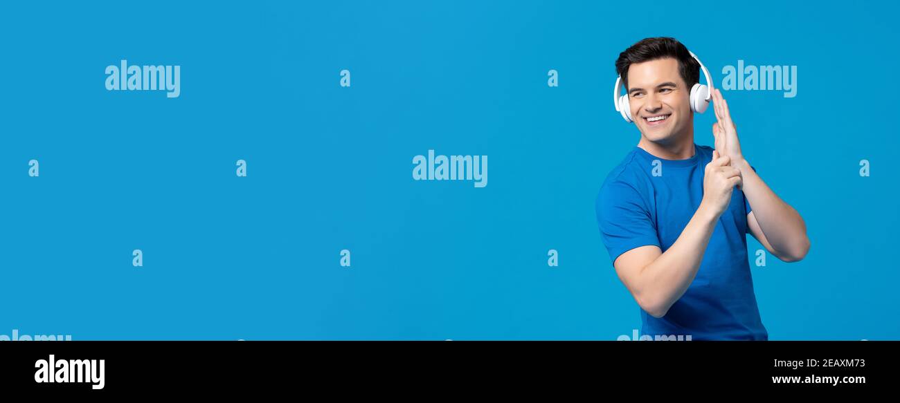 Nice smiling American man wearing headphone enjoyed listening to his favourite songs isolated on blue banner background with copy space Stock Photo
