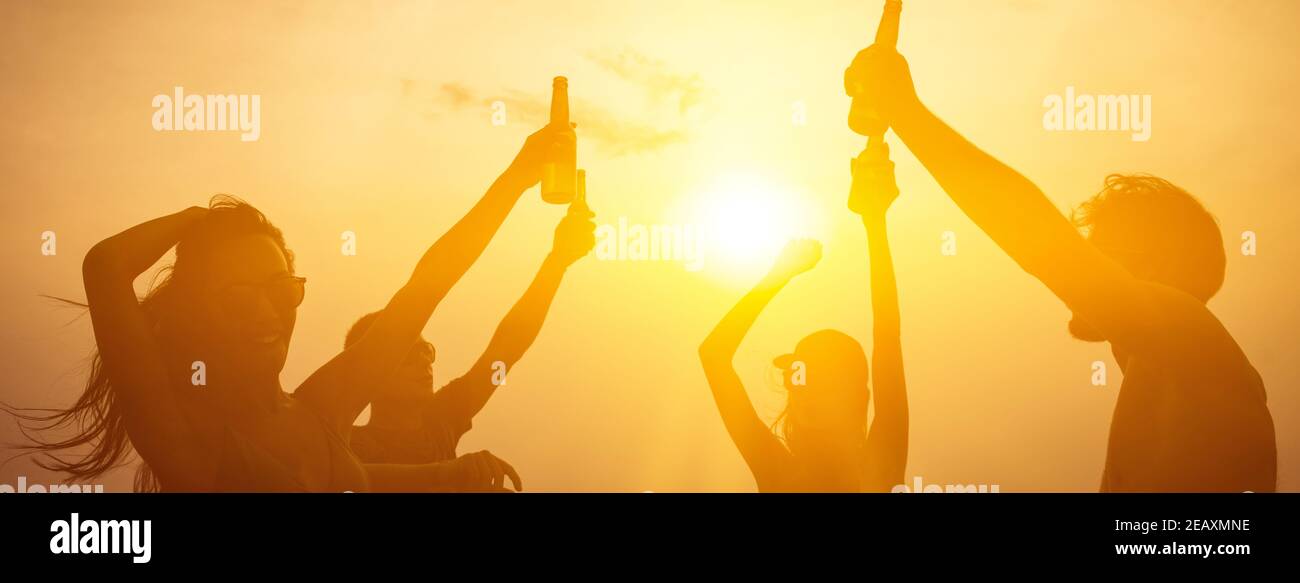 Group of attractive young friends enjoying drinking alocohol at the beach  in sunset banner background Stock Photo - Alamy