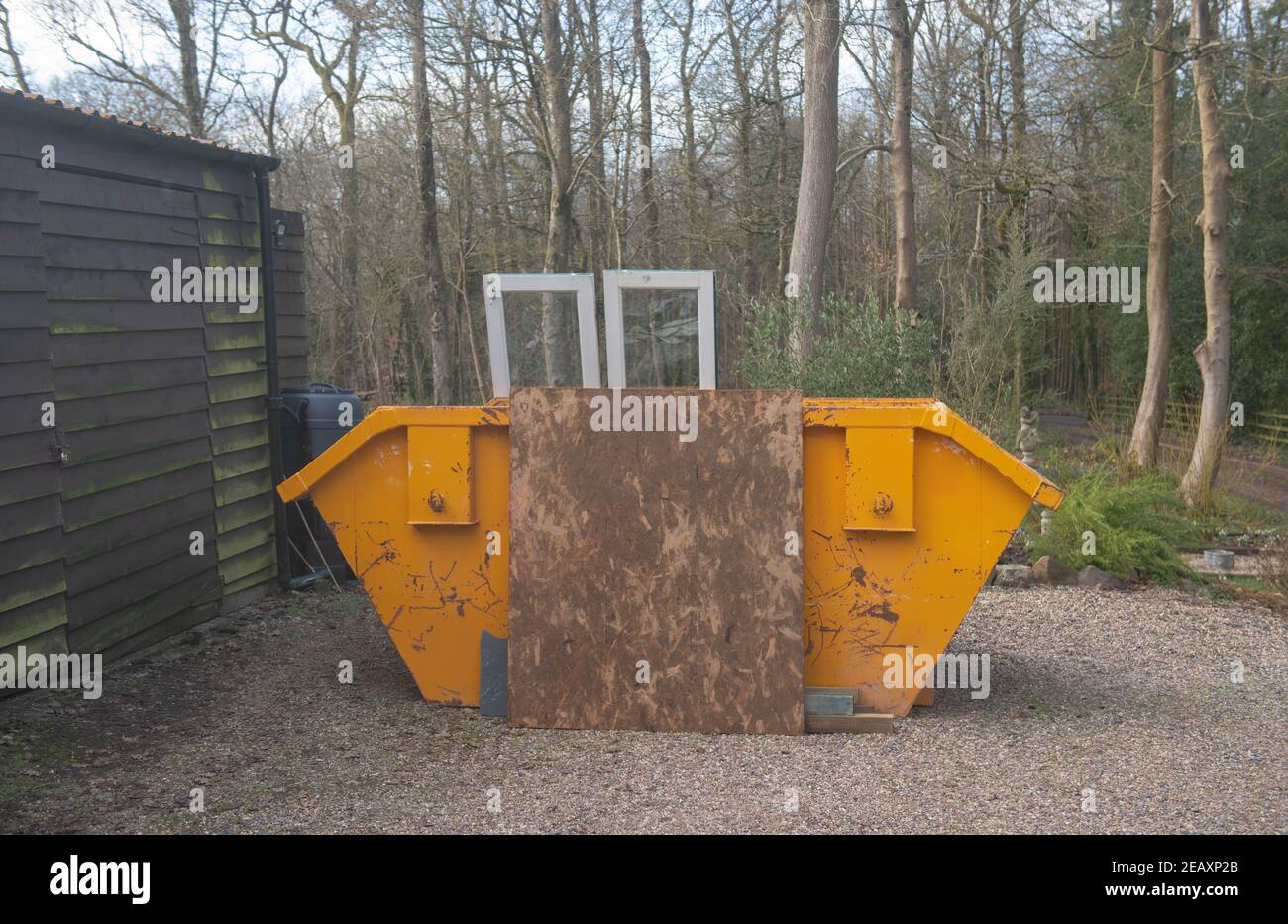 Bright Yellow Builders Skip Next to a Wooden Building on a Construction ...