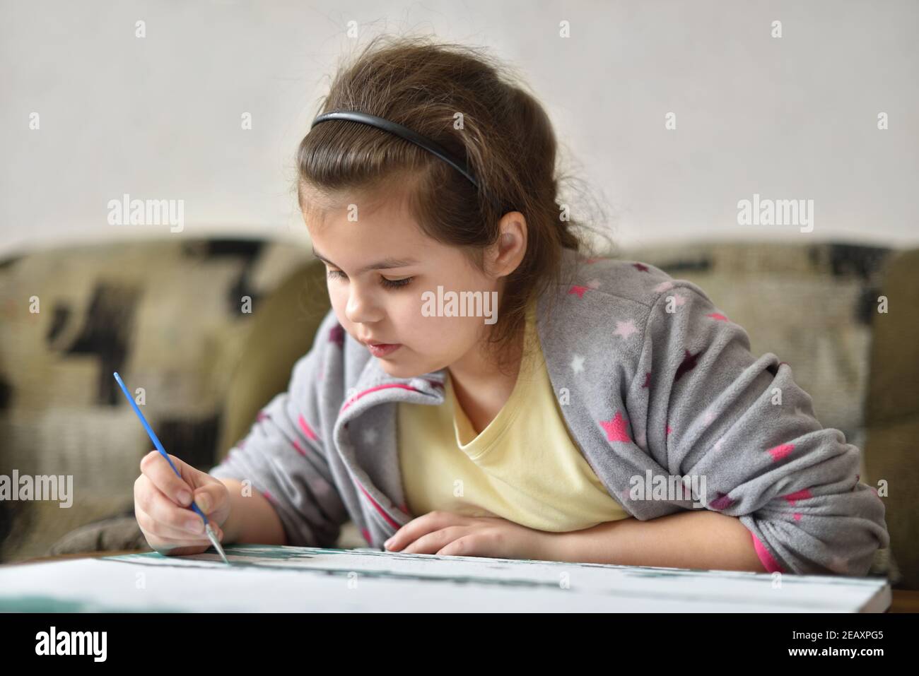 Child girl of 9 years old draws a picture with paints at home Stock Photo