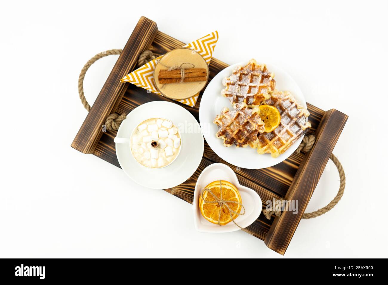Early breakfast coffee with marshmallows and a stick of cinnamon and Belgian waffles lie on a wooden tray Stock Photo