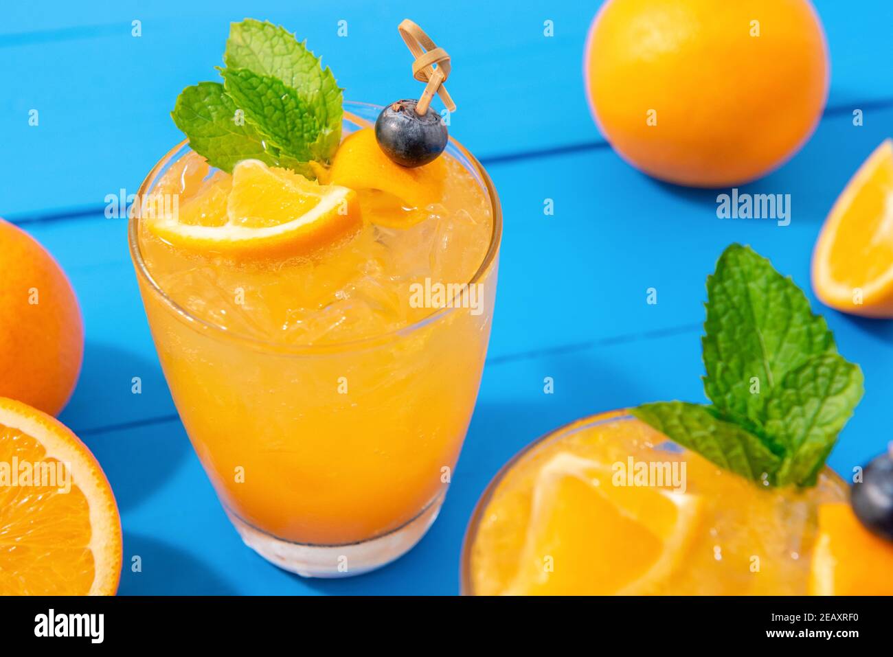 Colorful fresh orange juice mocktail drinks on blue table background Stock Photo