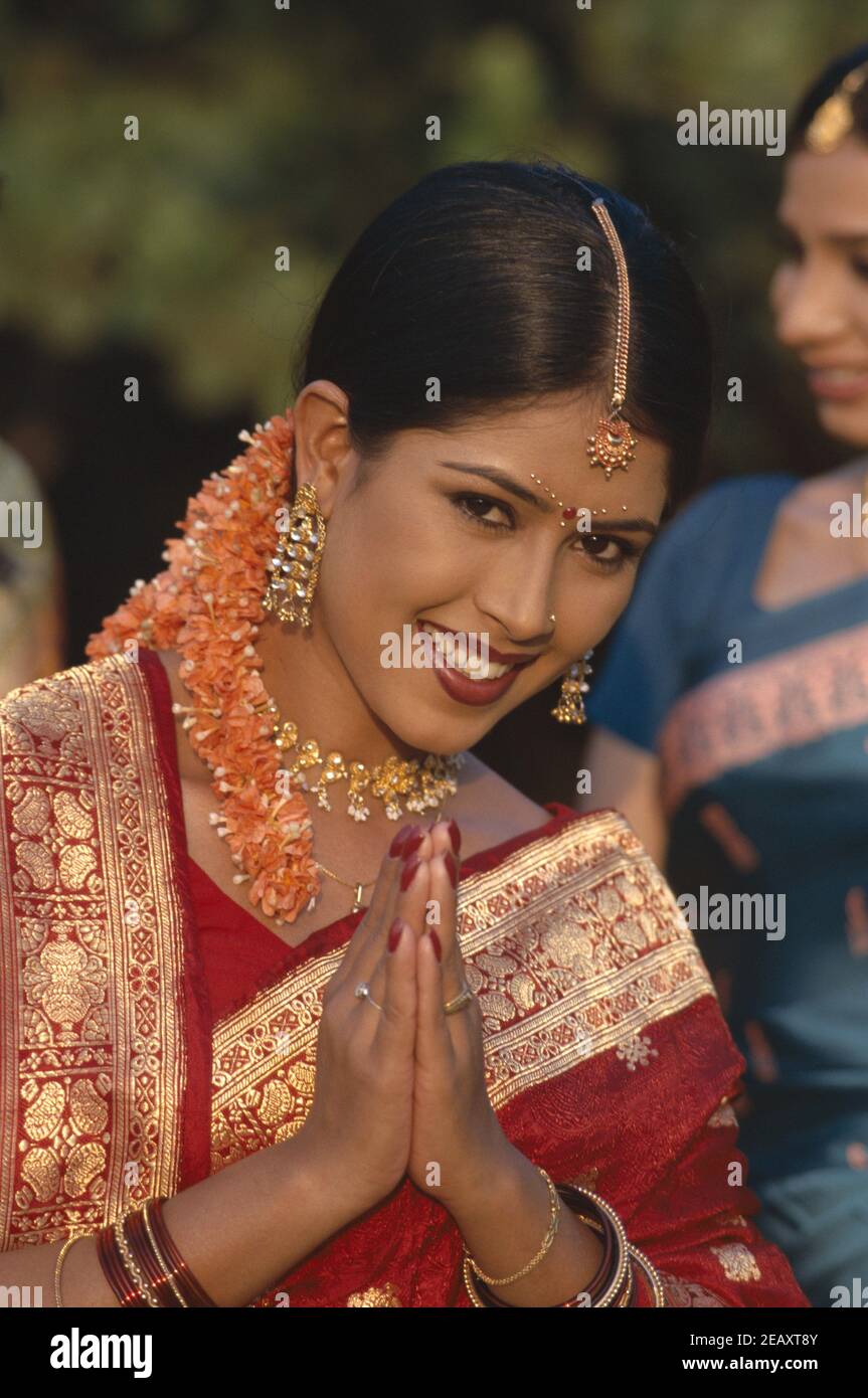Asia, India, Mumbai, model released portrait of a beautiful smiling Indian woman wearing the traditional sari dress in namaste greeting pose Stock Photo