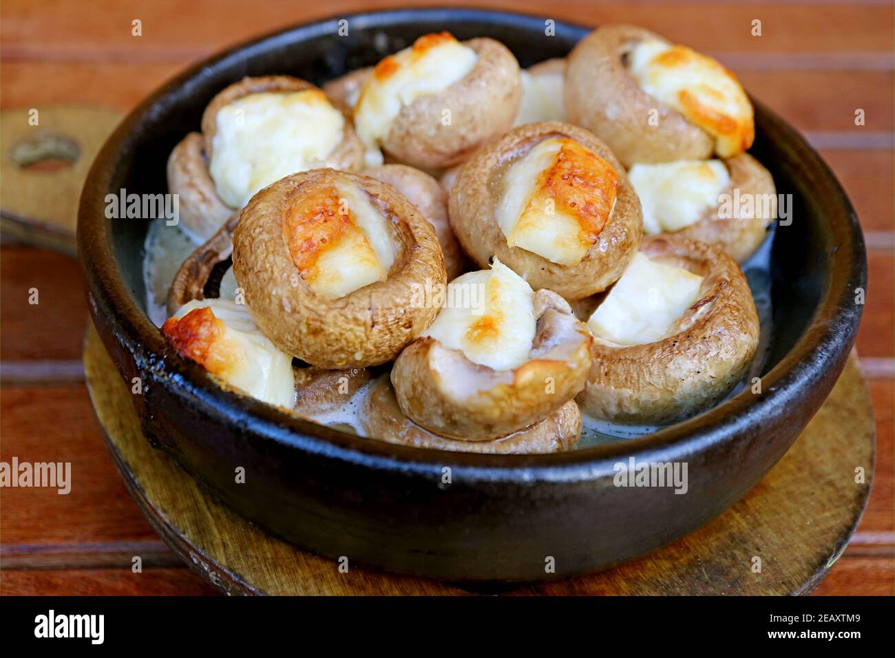 Closeup of Mouthwatering Soko Ketze or Georgian Stuffed Mushrooms with Sulguni Cheese in a Clay Dish Stock Photo