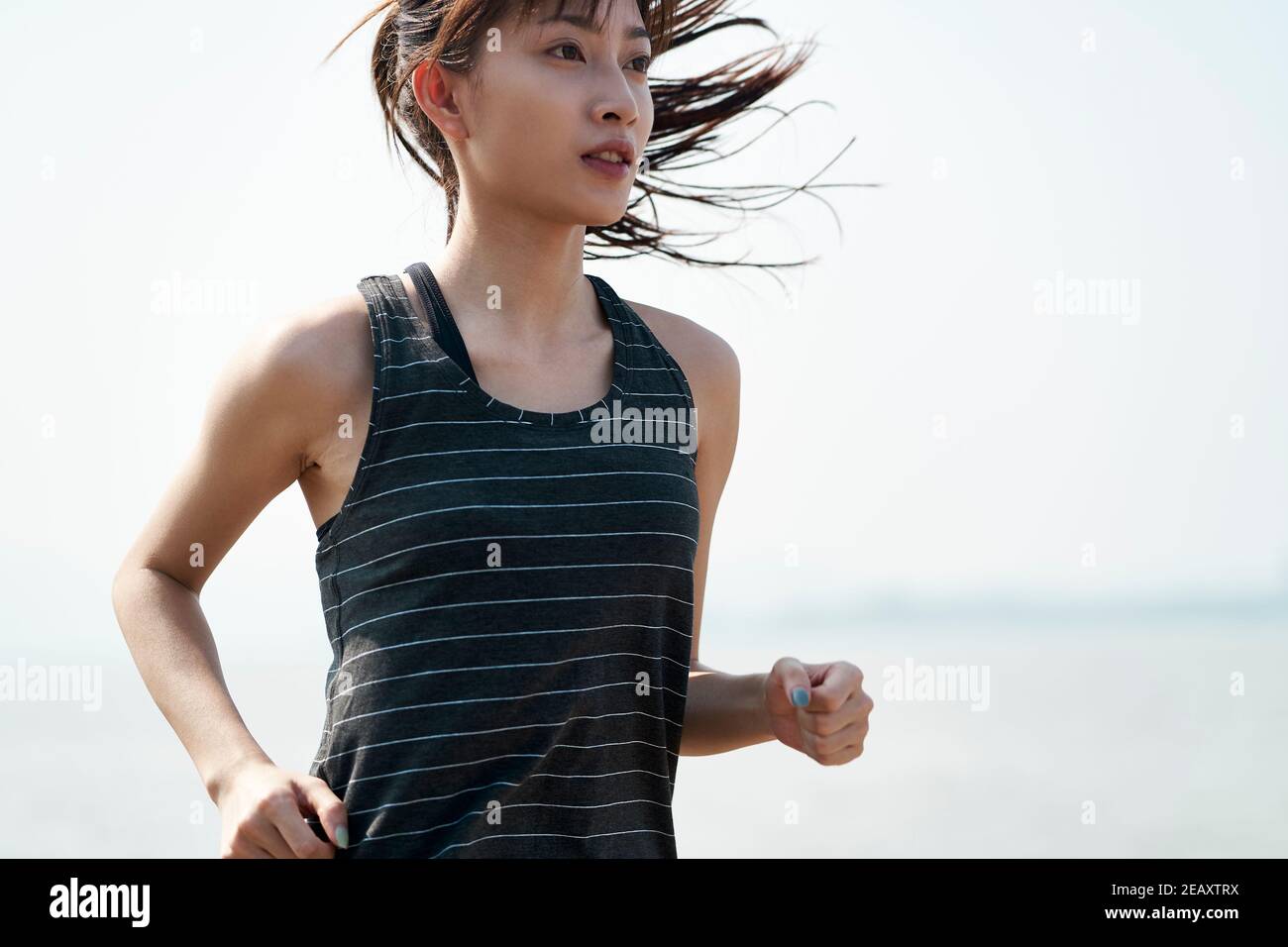 young asian woman female jogger running by the sea Stock Photo