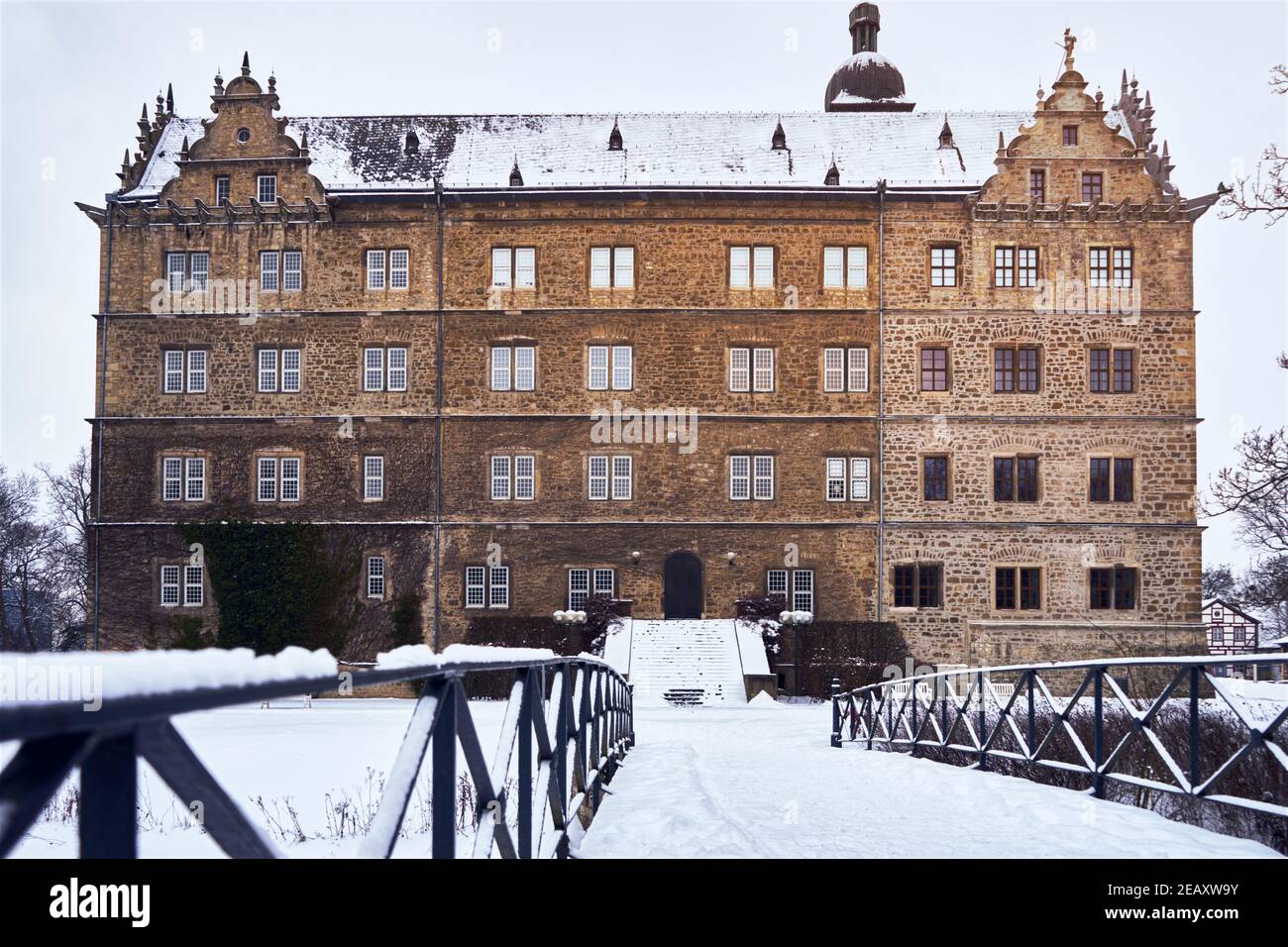 Rear side of Wolfsburg Castle in winter with view from a snow-covered bridge over the millrace Stock Photo