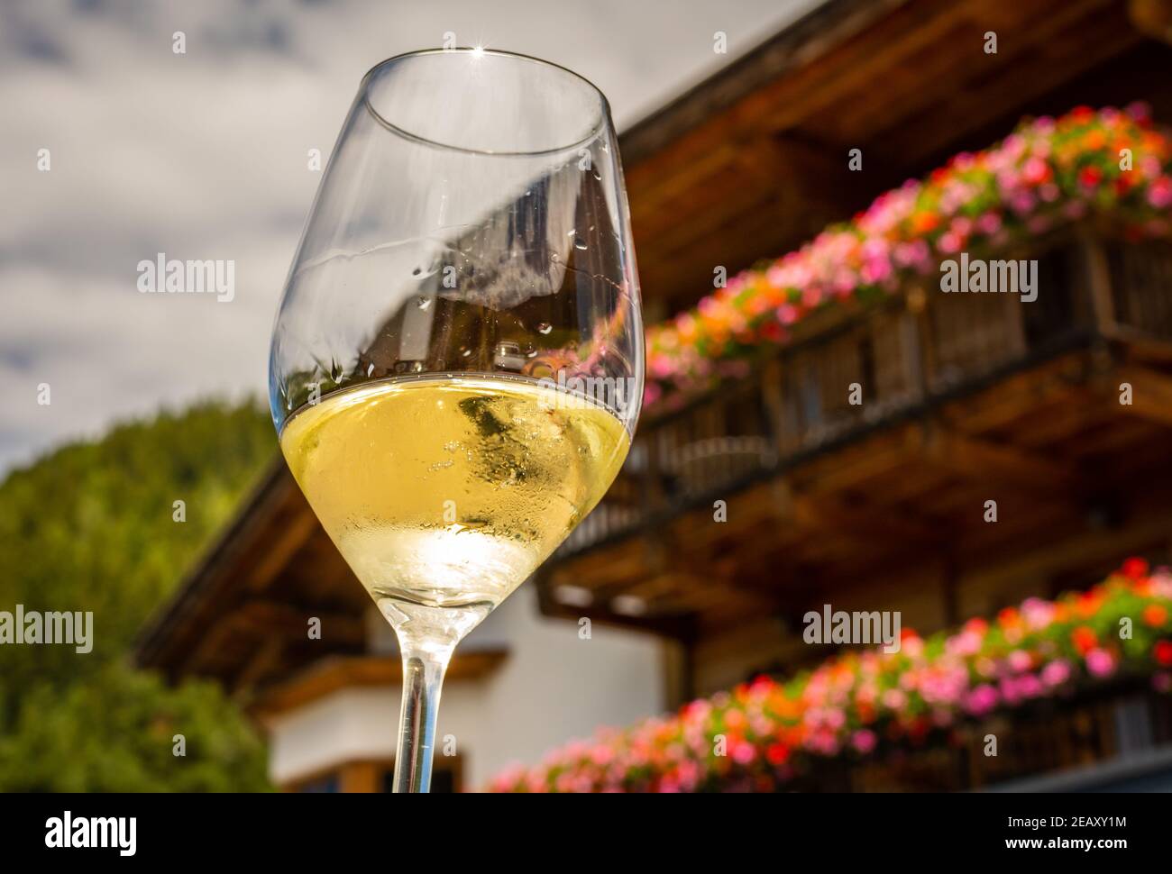 Glass of  white wine on a typical South Tyrolean house background. Hiking in Dolomites, South Tyrol, northern Italy Stock Photo