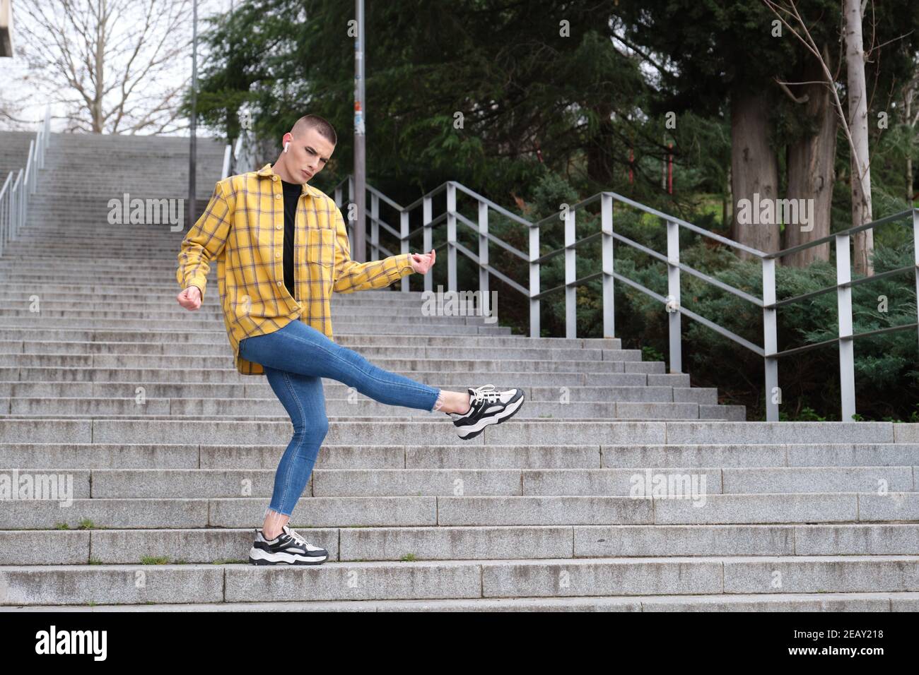 Handsome young man wearing make up, dancing on stairs. Non binary androgynous guy. Stock Photo