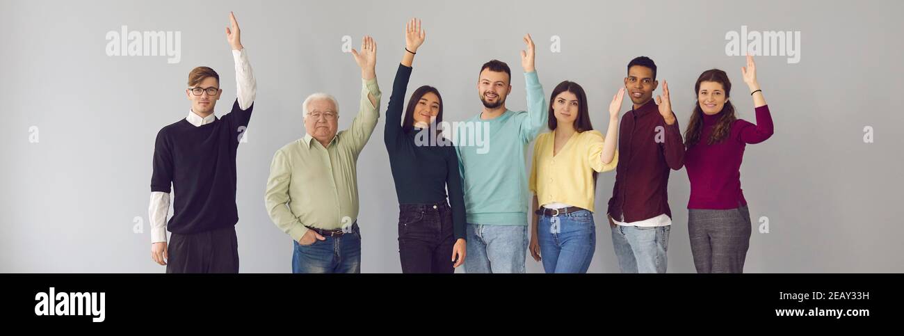 Group portrait of diverse people standing with arms raised and voting ...