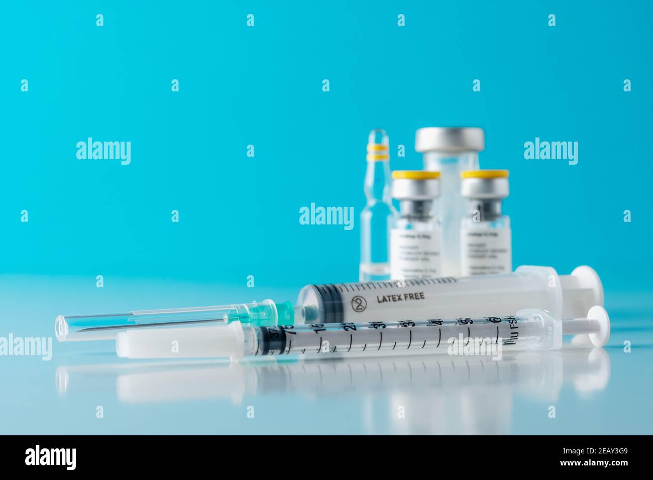 Vaccine vial glass with a syringe on blue background. Medicine ...