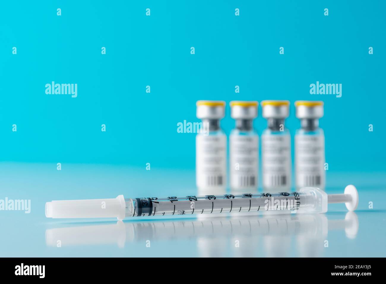 Vaccine vial glass with a syringe on blue background. Medicine ...
