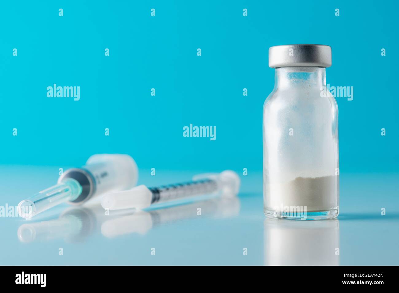 Vaccine vial glass with a syringe on blue background. Medicine ...