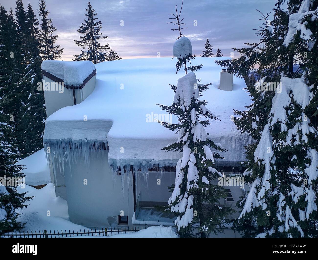 Small modern lodge or cabana covered in snow, surrounded by icy evergreens overlooking the Carpathian Mountains, winter landscape in Ranca, Romania Stock Photo