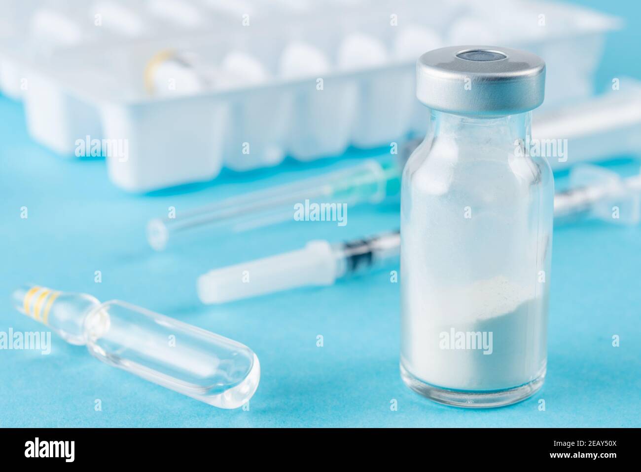 Vaccine vial glass with a syringe on blue background. Medicine ...