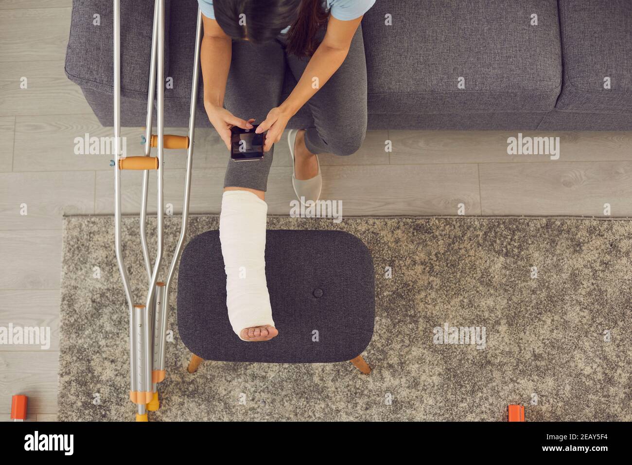 Woman photographing her leg in a plaster cast for an online consultation with a doctor. Stock Photo