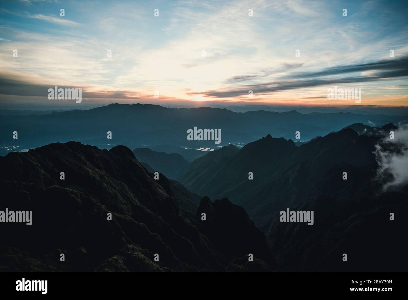 Sun-set moment, scenery of mountains in layers, dark violet purple silhouette panoramic view. Stock Photo