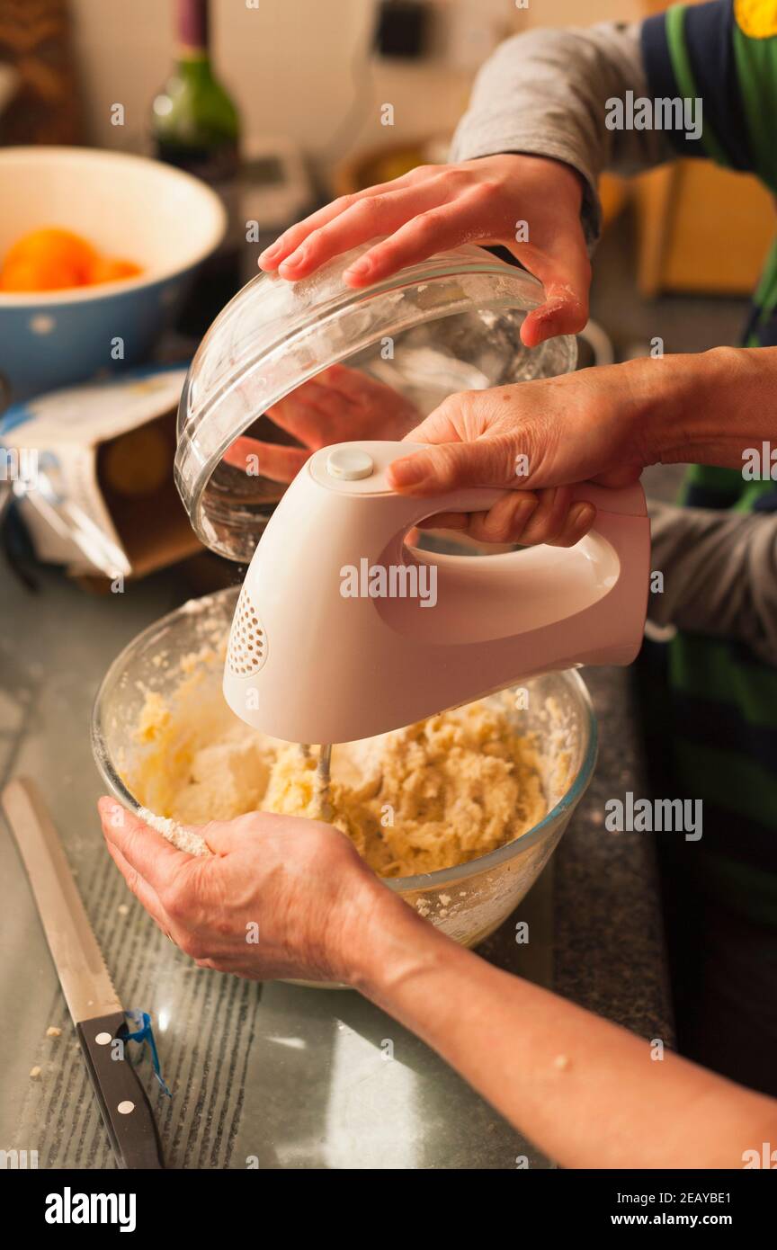 A 12 year old boy making cookies with his grandmother at home in England , Britain , Uk Stock Photo