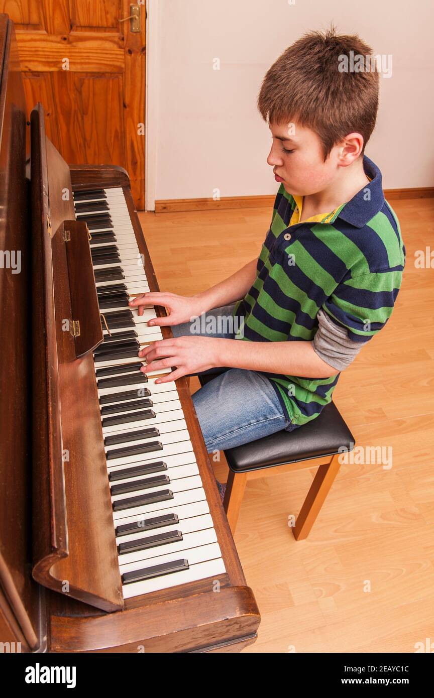 A 13 year old boy playing on a piano Stock Photo