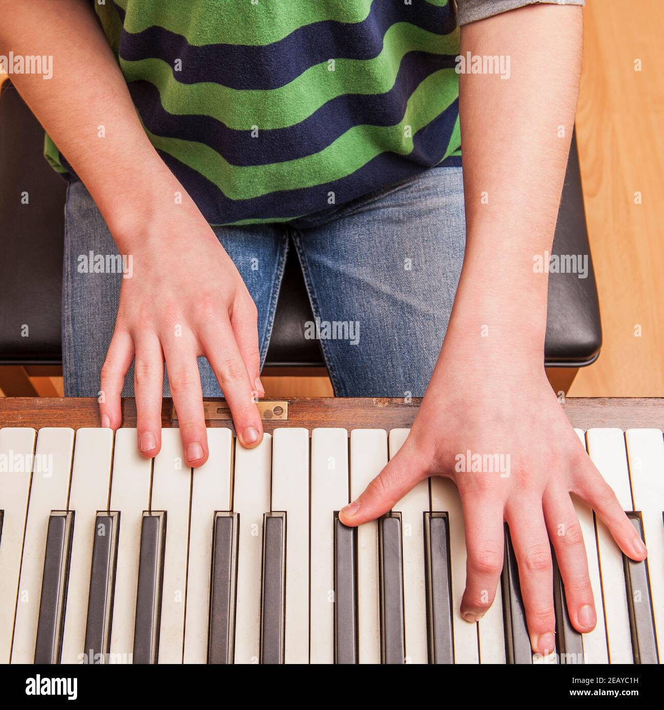 A 13 year old boy playing on a piano Stock Photo