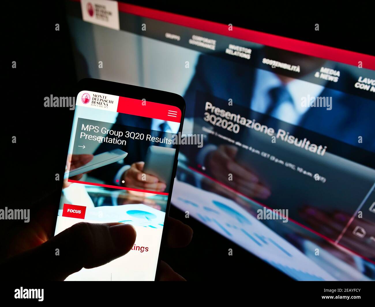 Person Holding Smartphone With Web Page Of Bank Banca Monte Dei Paschi Di Siena On Screen In Front Of Monitor Focus On Center Of Phone Display Stock Photo Alamy