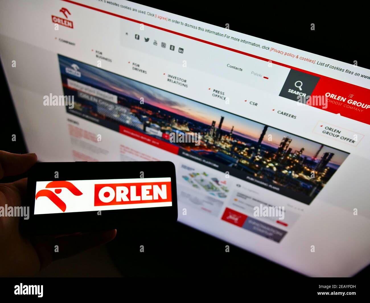 Person holding smartphone with logo of Polish oil company Polski Koncern Naftowy (PKN) Orlen on screen in front of website. Focus on phone display. Stock Photo