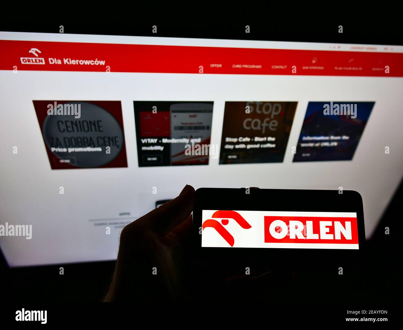 Person holding mobile phone with logo of Polish oil and gas company PKN Orlen on screen in front of business website. Focus on cellphone display. Stock Photo