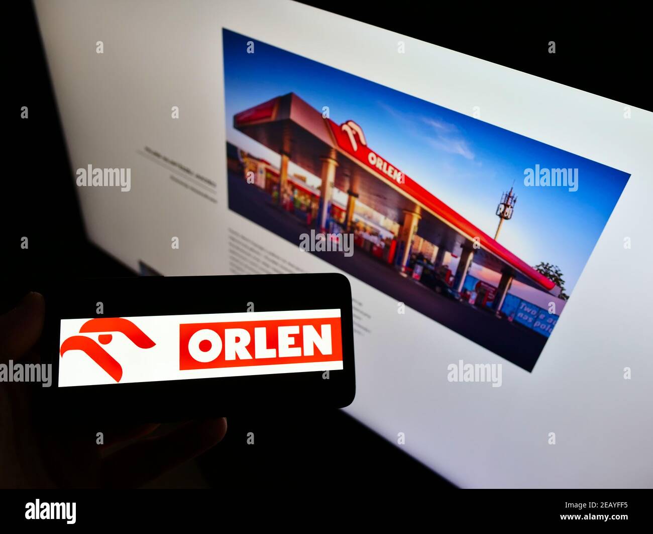 Person holding cellphone with logo of Polish oil and gas company PKN Orlen on screen in front of business website. Focus on smartphone display. Stock Photo