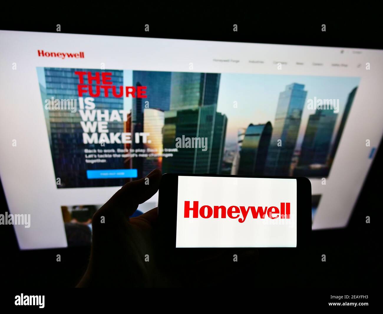 Person holding smartphone with logo of US conglomerate Honeywell International Inc. on screen in front of website. Focus on phone display. Stock Photo