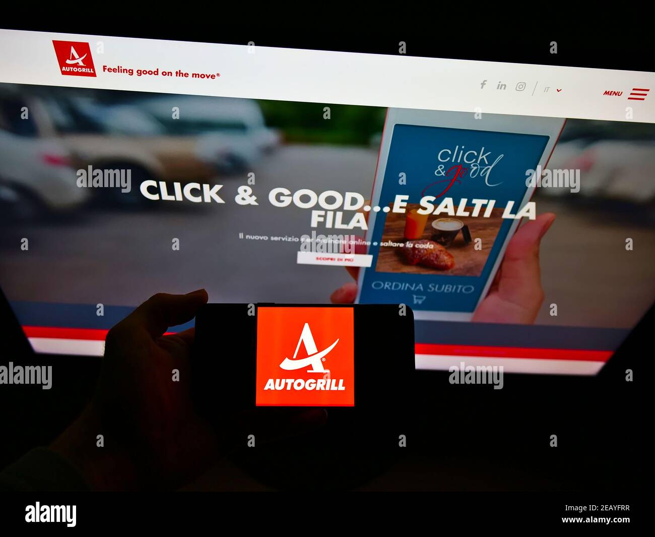 Person holding mobile phone with logo of Italian catering company Autogrill S.p.A. on screen in front of web page. Focus on cellphone display. Stock Photo