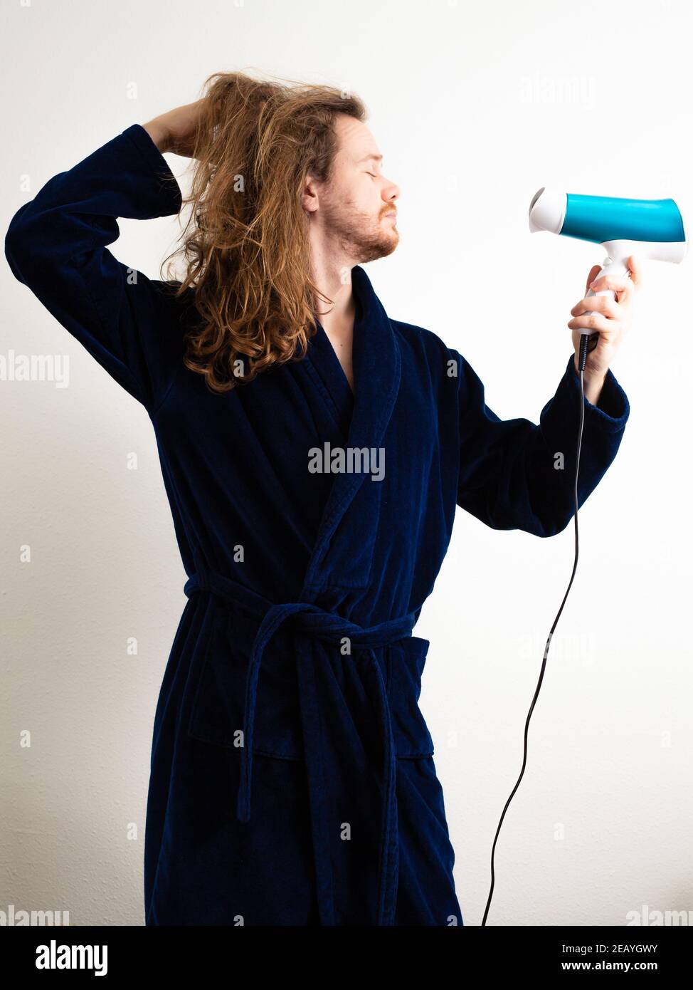 ZOETERMEER, NETHERLANDS - Dec 16, 2020: Man drying his hair in a Man in a feminine way Stock Photo