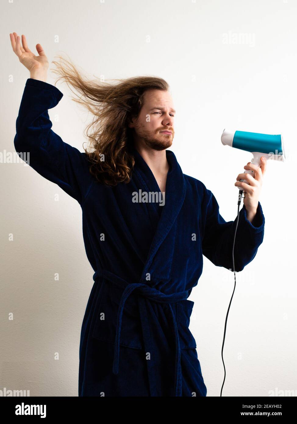 ZOETERMEER, NETHERLANDS - Dec 16, 2020: Man drying his hair in a Man in a feminine way Stock Photo