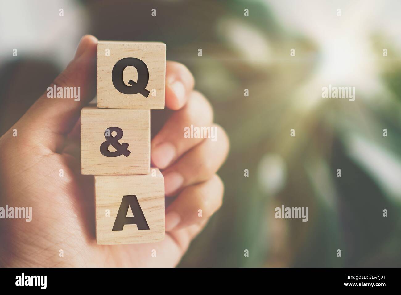 Q and A alphabet on wooden cube in hand hold with background. Question ...