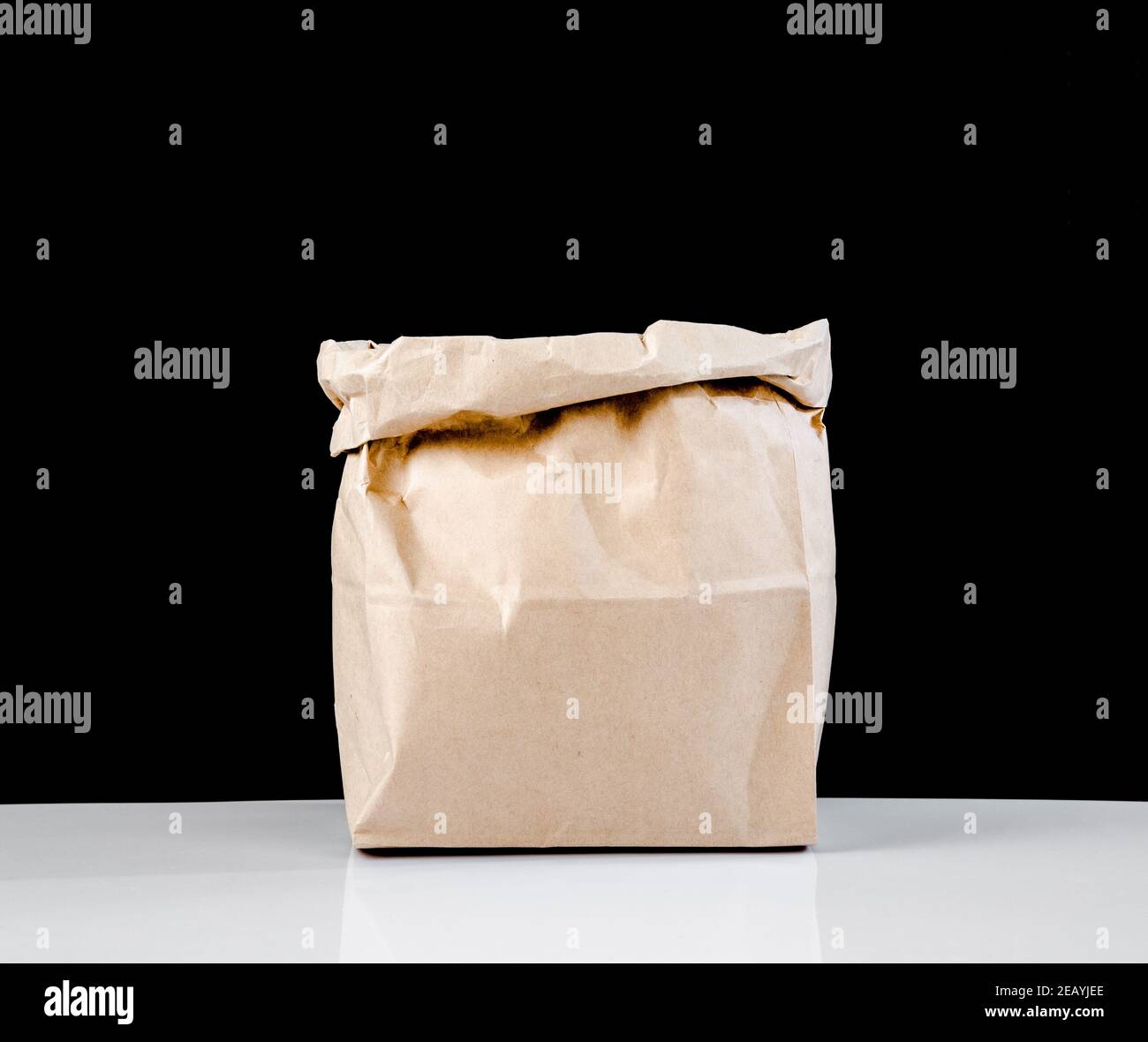 The empty open brown paper bag on black background. Stock Photo