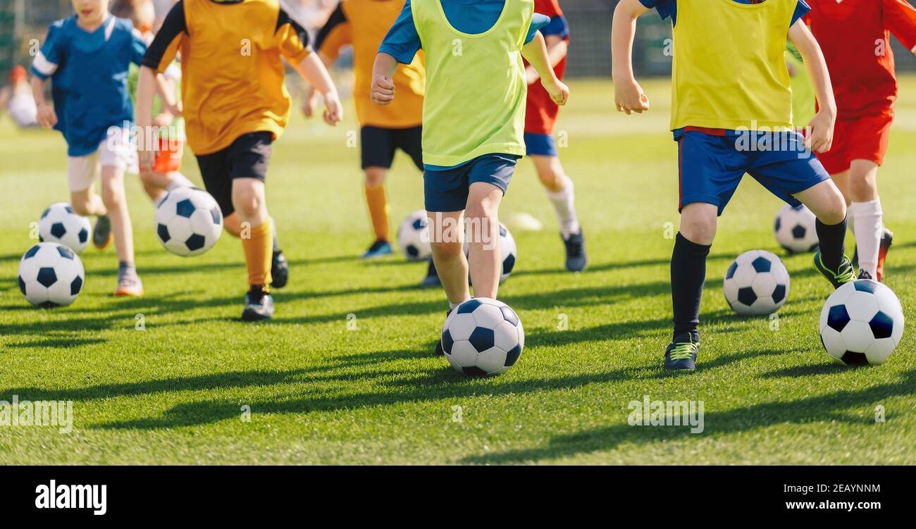 Football soccer children training class. Kids practicing football on grass field. Group of school children running and kicking soccer balls on summer Stock Photo