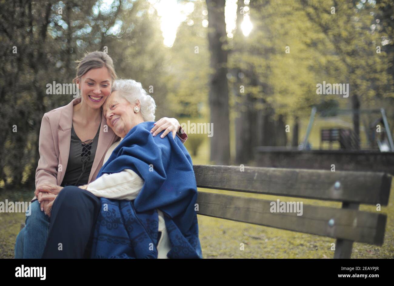 Granddaughter sitting on a bench in a park with her grandmother and ...
