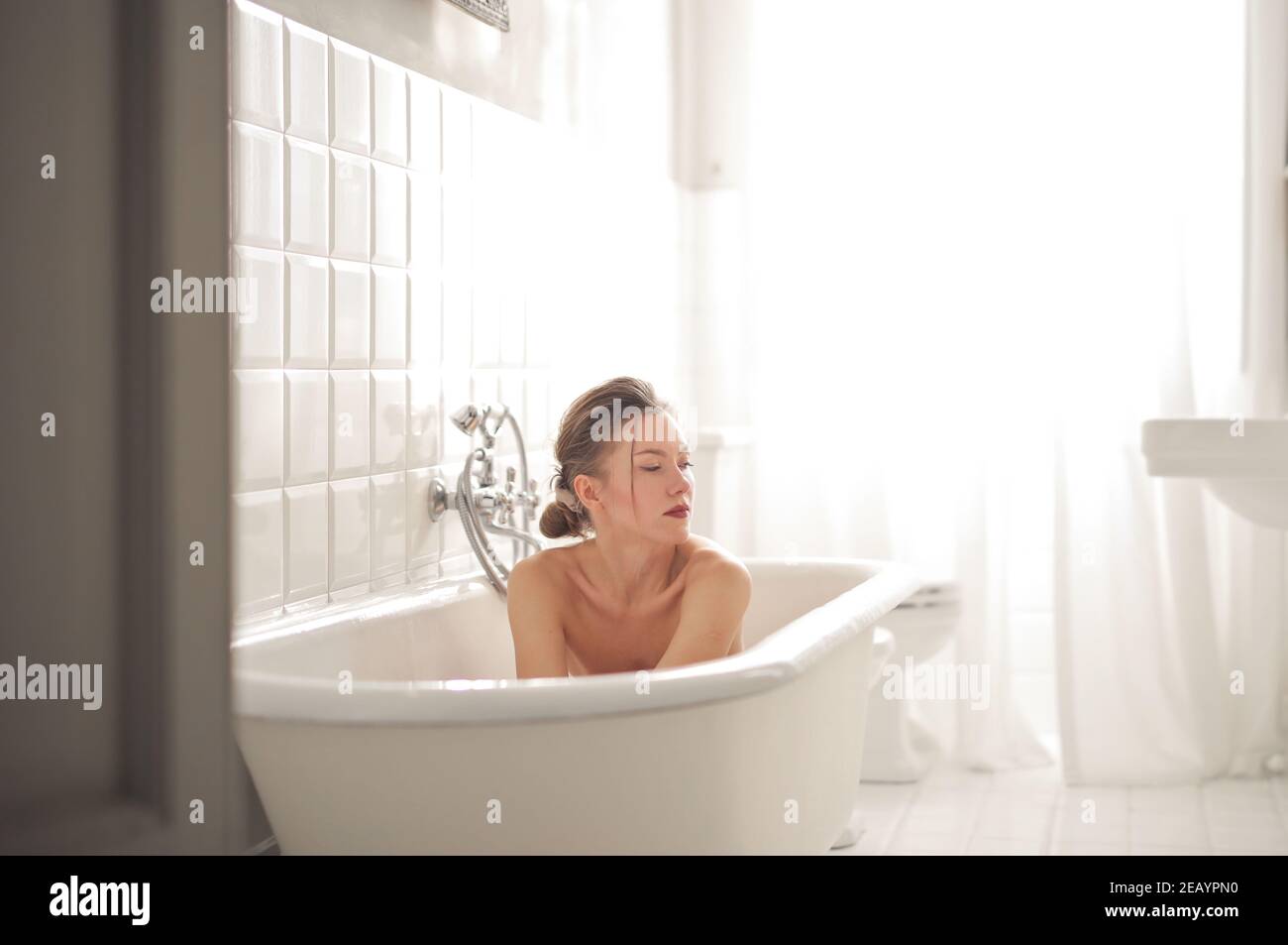 Young European female in a white modern bathtub Stock Photo