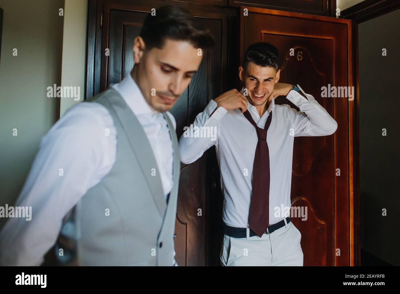Groom and best man putting on the suit before the wedding Stock Photo ...
