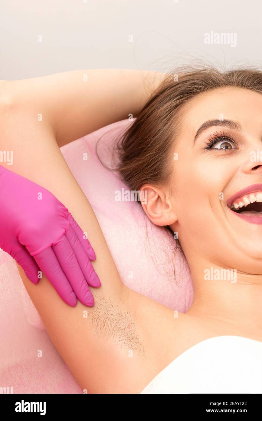 Young woman during armpit examination before waxing procedure laughing in a beauty salon Stock Photo