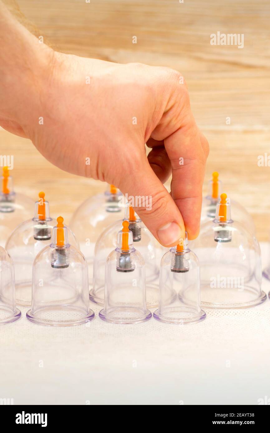 Hand of massage therapist taking vacuum cups from the table before