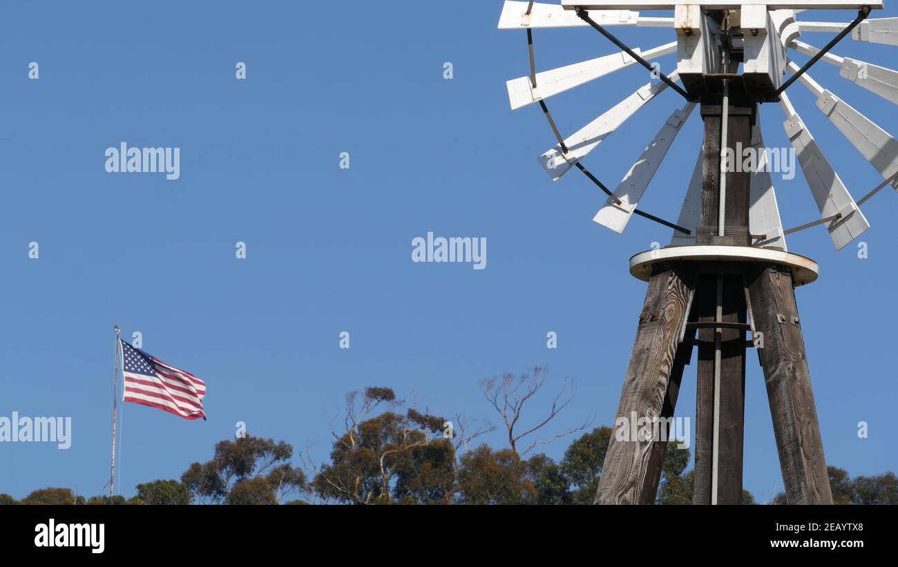 Classic retro windmill, bladed rotor and USA flag against blue sky ...