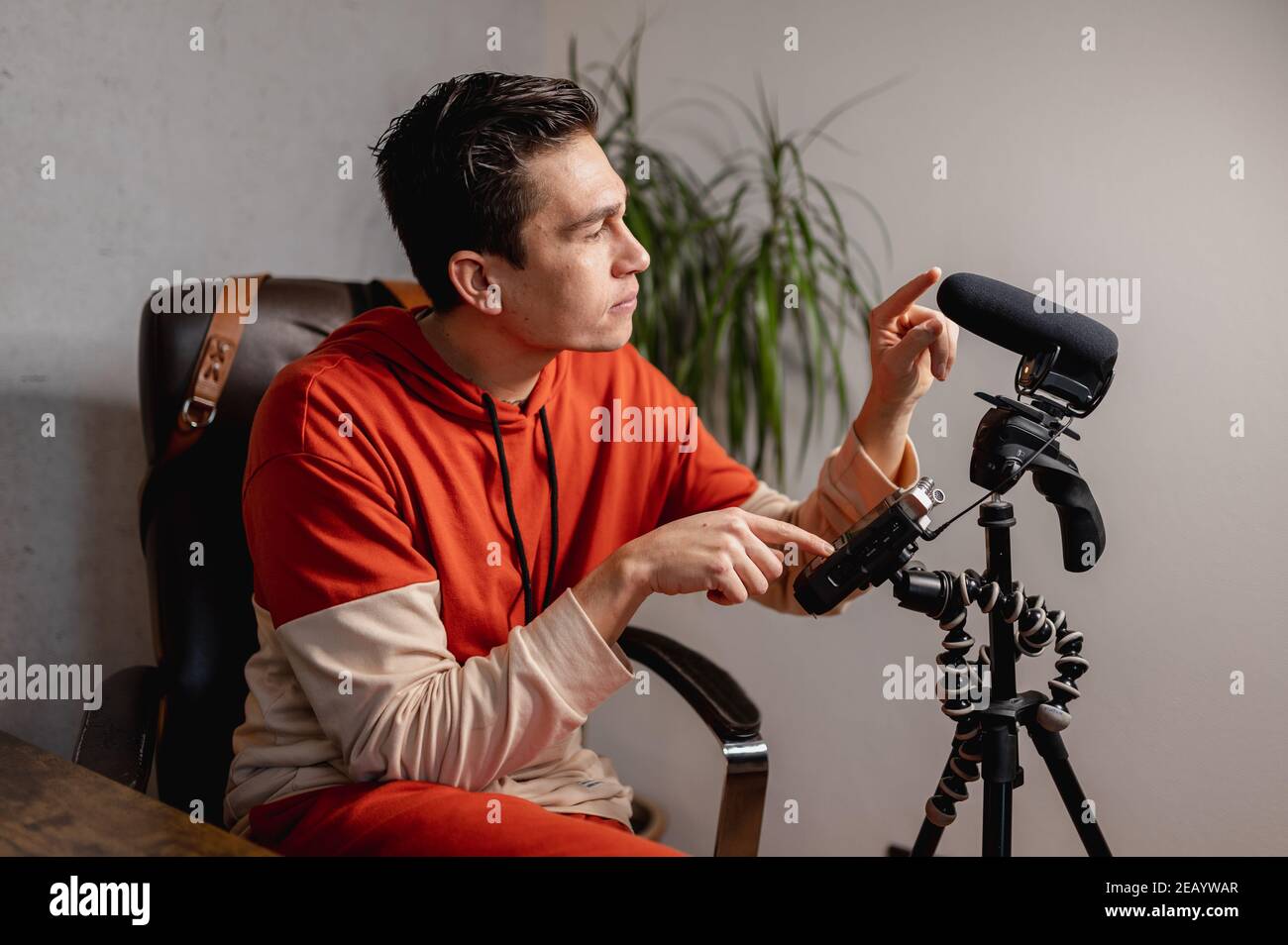 Young man setting the camera and microphone to take a video. Vlogger, teaching concept. Stock Photo