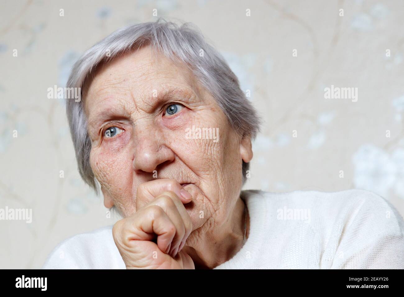 Elderly woman with peaceful expression thought about something. Female with gray hair and wrinkled skin, concept of memories, old age Stock Photo