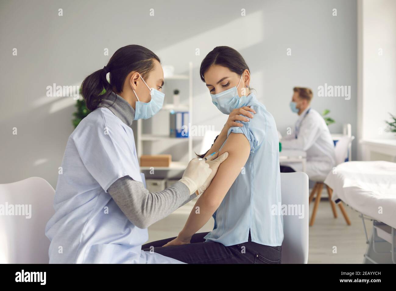 Young woman gets vaccinated at clinic or health center during global Covid-19 pandemic Stock Photo