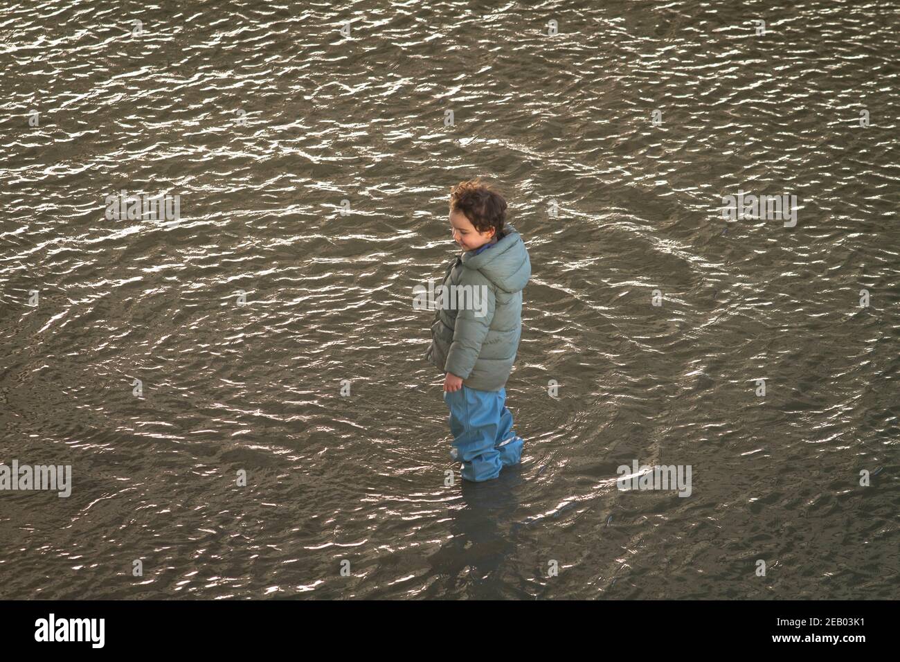 flood of the Rhine on February 4th. 2021, child stands in the water on the flooded banks of the Rhine in Deutz, Cologne, Germany.  Hochwasser des Rhei Stock Photo