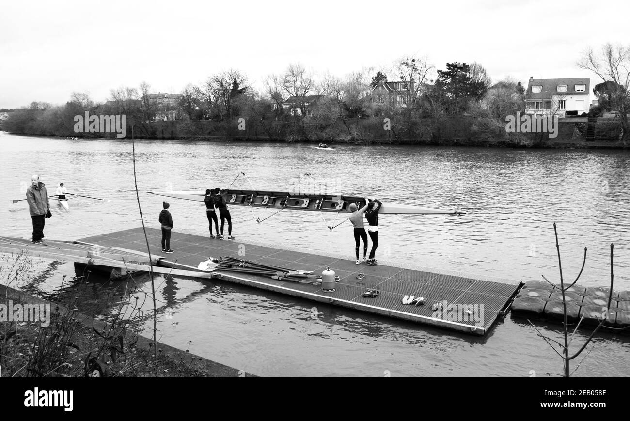 ILE-DE-FRANCE, FRANCE - JANUARY 26, 2019: Junior rowers training at Marne river. Boys carrying and getting the boat in the water. Black white photo. Stock Photo