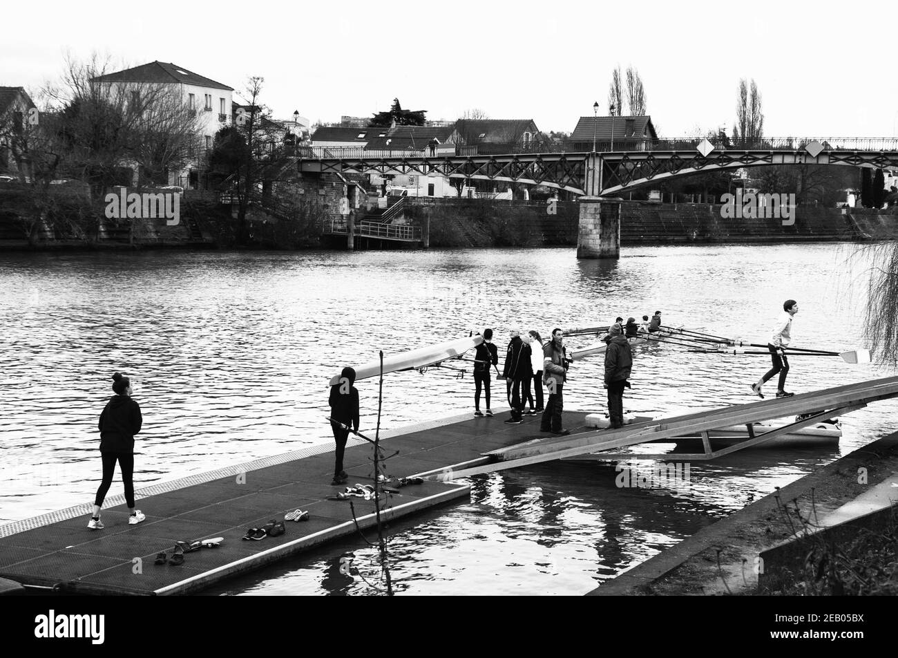 ILE-DE-FRANCE, FRANCE - JANUARY 26, 2019: Junior rowers training at Marne river. Boys carrying and getting the boat in the water. Black white photo. Stock Photo