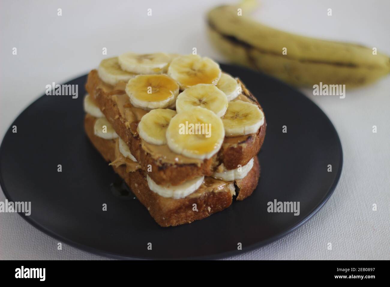 Peanut butter banana honey toast sandwich, an easy breakfast idea. Shot on white background. Stock Photo