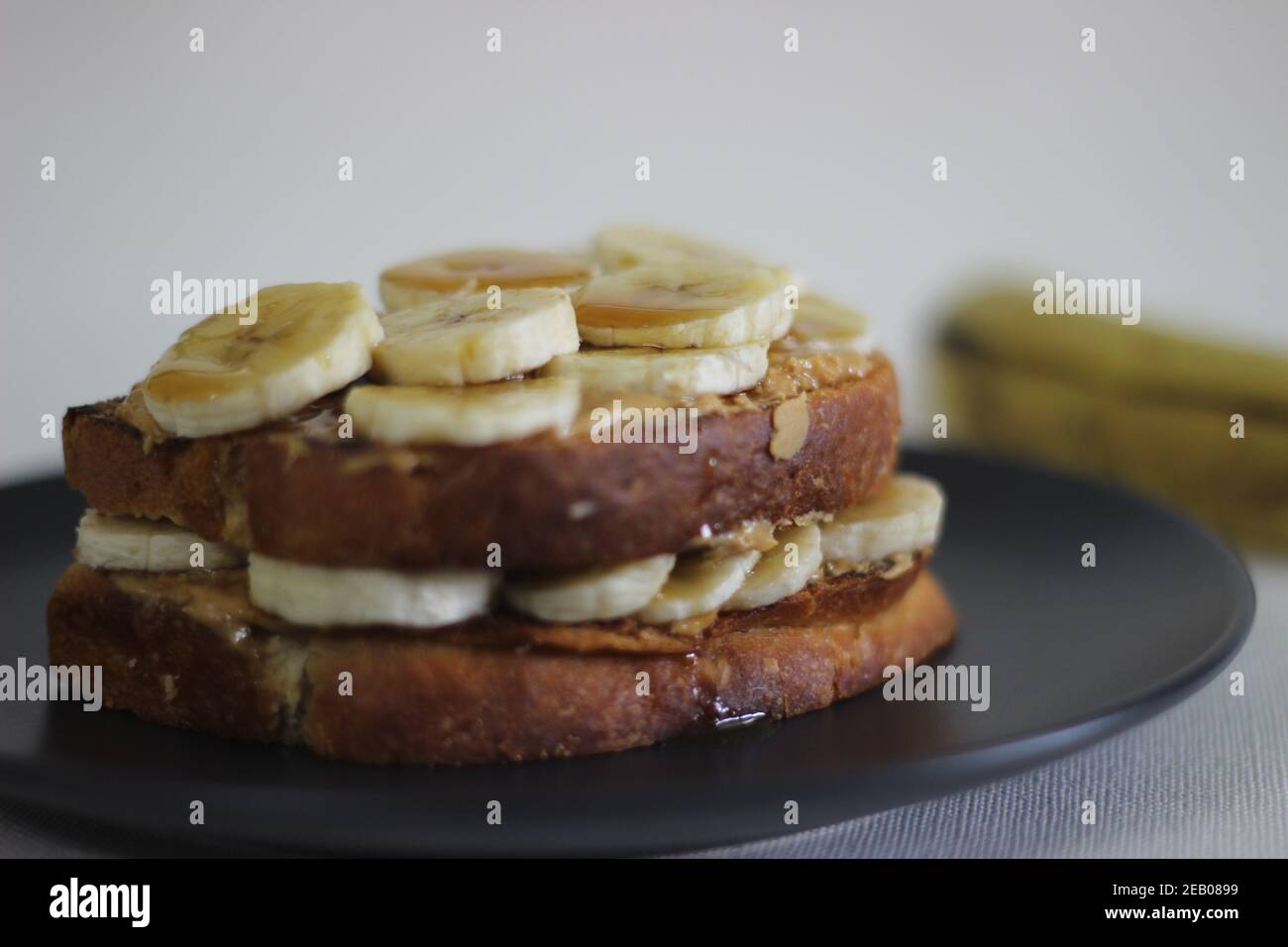 Peanut butter banana honey toast sandwich, an easy breakfast idea. Shot on white background. Stock Photo