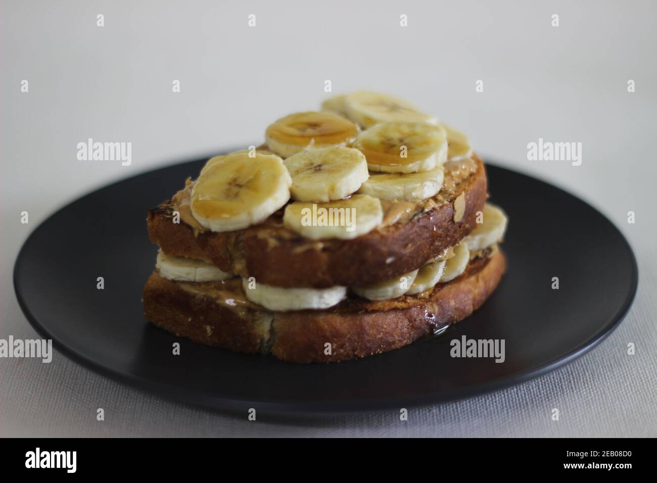Peanut butter banana honey toast sandwich, an easy breakfast idea. Shot on white background. Stock Photo