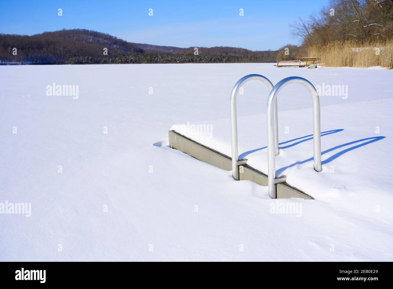 Frozen, snow covered lake with ladder and dock for swimmers. Stock Photo